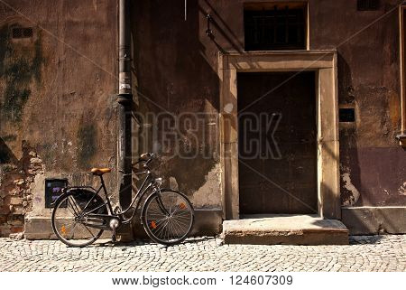 Bicycle standing next to an old wall and door in European city