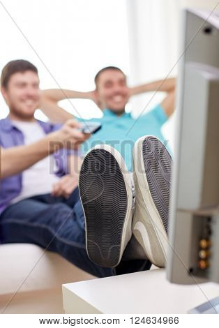 friendship, sports, people and entertainment concept - close up of happy male friends with remote control watching tv at home
