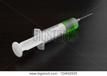 Single Syringe With Green Liquid On The Black Wood  Background