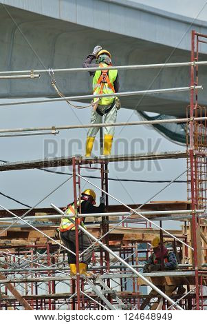 SELANGOR, MALAYSIA -FEBRUARY 23, 2016: Construction workers wearing safety harness and installing scaffolding at high level in the construction site in Selangor, Malaysia.