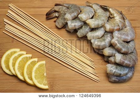 Many Raw  Shrimps On Skewer With Lemon On Wooden Background