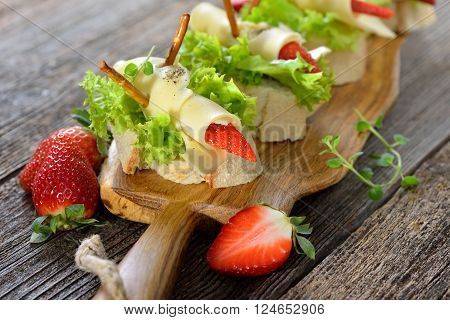 Delicious canapes with cheese rolls and strawberries on Italian ciabatta bread with lettuce leaves