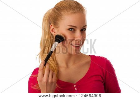 Woman applying pouder with cosmetics brush on cheeck making makeup.