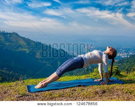 Woman doing Hatha yoga asana Purvottanasana plank pose  outdoors in mountains