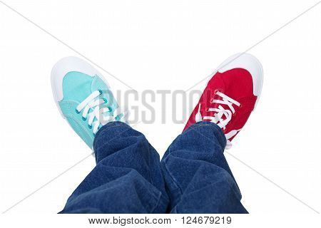 jeans and wearing different sneakers on legs