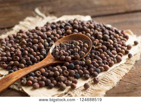 Raw organic roveja beans with a spoon on a wooden table