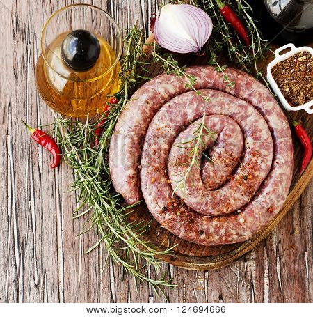 raw beef sausages on a cast-iron pan with rosemary and spices on a wooden table South African boerewors