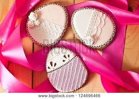 Easter homemade gingerbread cookie with pink ribbon over wooden table. Colorful image top view