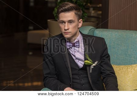 Young confident businessman sitting in armchair. Close up.