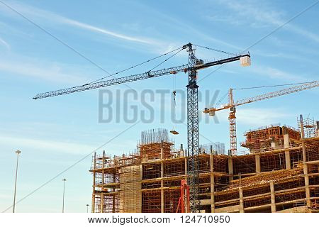An urban building under contsruction with cranes working to move building materials on site
