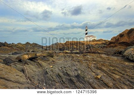 Cap de Favaritx eroded rocks, landscape with weathered ground and a lighthouse on background, Menorca, Spain