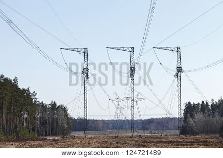 electricity transmission pylon silhouetted against blue sky. In the woods, at sunset.