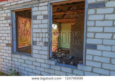An old abandoned brick house with a broken window, closeup. As background for design of crisis.