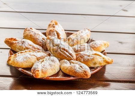 freshly baked apple pies on plate, wooden table