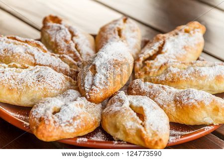 freshly baked apple pies on plate, wooden table