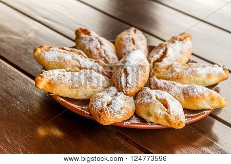 freshly baked apple pies on plate, wooden table