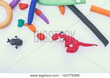 Creating red dinosaur and whale clay model, on white background. Animals from play dough. Education concept.
