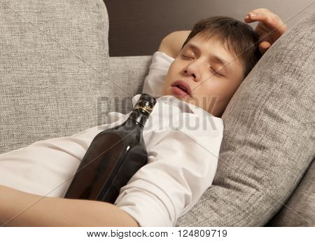 Drunkard. A young man with a drinking problem is relaxing on a sofa