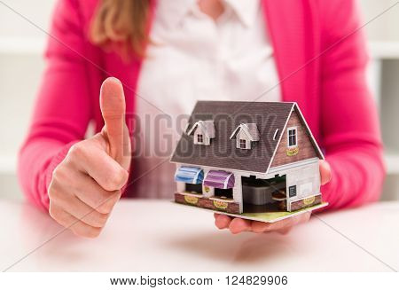Mortgage broker showing thumb up sitting at the desk in office