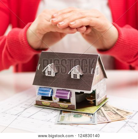 Closeup of miniature house standing on dollars banknotes on desk