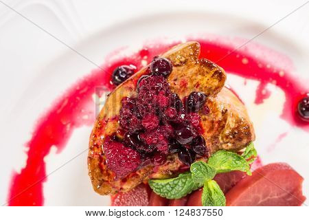 Grilled foie gras covered with forest berries and sliced pear with red sauce. Macro. Photo can be used as a whole background.