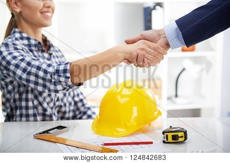 Happy smiling woman architect meeting customer at workplace. Project development concept.