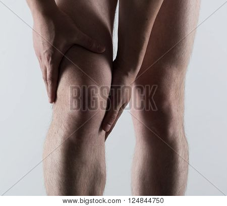 Knee spasm or injury. Young man touching his sore leg.