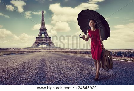 Paris. Eiffel tower. Young business woman hurrying up with luggage and umbrella on highway. Business trip to France concept.