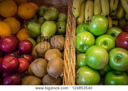 Plums, apples, pears and oranges in a bowl on a table on a self service breakfast counter in a hotel