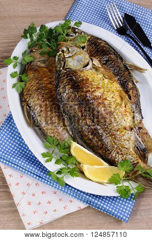 Fried crucian carp in a plate on the table with napkins