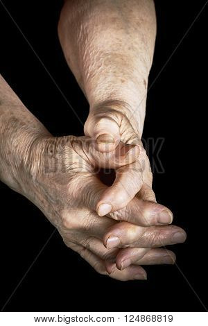 Old woman clasped in her hands on a black background