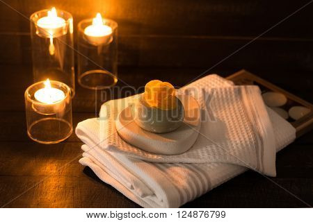 ?andle toweles and soap with a yellow flower on a wooden background spa concept