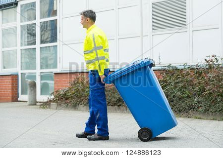 Male Worker Walking With Dustbin On Street