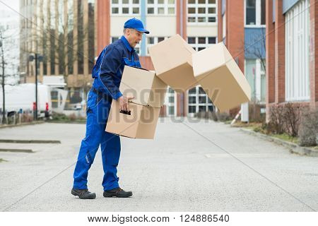 Delivery Man With Falling Stack Of Boxes On Street