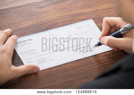 Close-up Photo Of Businessman Filling Blank Cheque