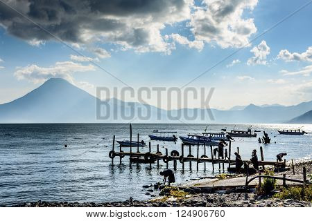 Lake Atitlan, Guatemala - April 3, 2016: Locals by the water in evening light at Lake Atitlan with San Pedro volcano behind in Guatemalan highlands.