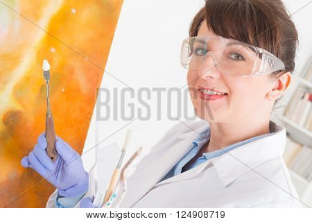 Artwork conservator at work with old painting wearing protective suit