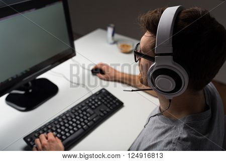 technology, gaming, entertainment, let's play and people concept - close up of young man in headset and glasses with pc computer playing game at home and streaming playthrough or walkthrough video