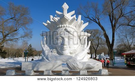 HARBIN CHINA - JANUARY 16 2016: people under a snowy sculpture during the 32nd Harbin Ice Festival. The main attraction is the Harbin Ice and Snow World which covers more than 750000 square meters. Its structures required more than 330000 cubic meters of