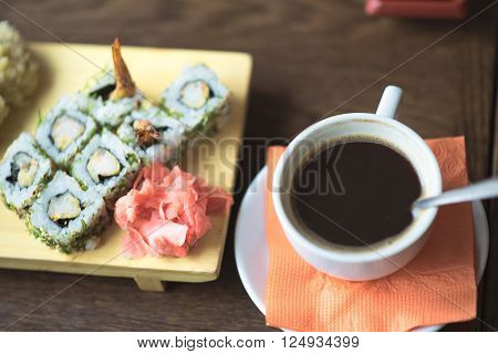 Photo female hands holding chopsticks for sushi, rolls close-up on the table is to persist cup of coffee or tea in a cafe