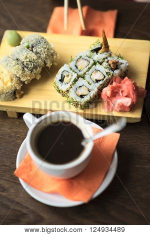 Photo female hands holding chopsticks for sushi, rolls close-up on the table is to persist cup of coffee or tea in a cafe