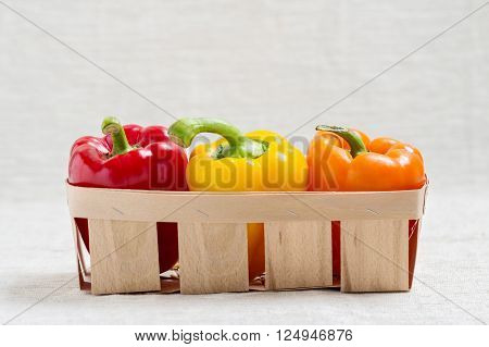 Fresh vegetables. Three sweet peppers in a basket of red yellow and orange.