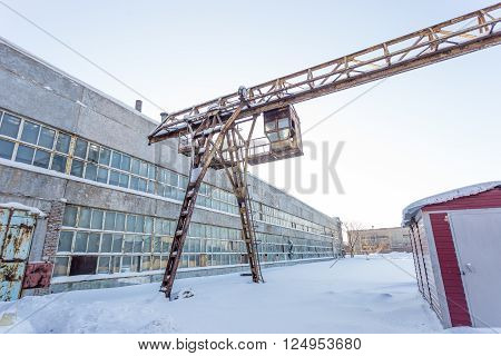 large industrial building in abandoned factory area with rusty lift at sunny day