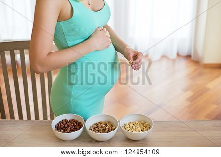 Pregnant woman with 3 bowls of nuts on the table