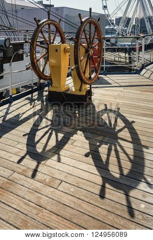 Steering wheel of the ship and its shadow on the deck.