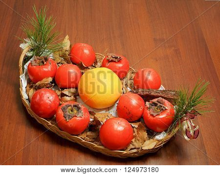 Composition of persimmon grapefruit and pine cone in the dish on table