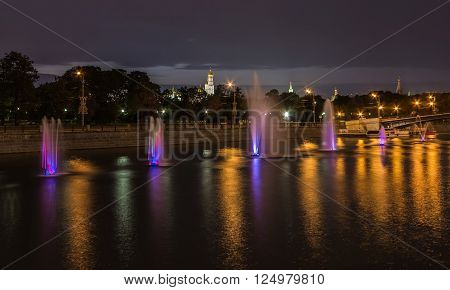 Fountains in dynamic near Kremlin in Moscow River at night with a cathedral on background