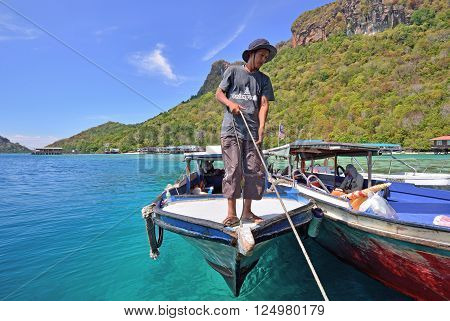 SEMPORNA, MALAYSIA - APRIL 18, 2015 - Unidentified man pulling a passenger boat rope in Bohey dulang Island, near Sipadan Island in Sabah Borneo.