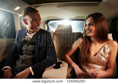 Young couple in the back of a limo looking at each other