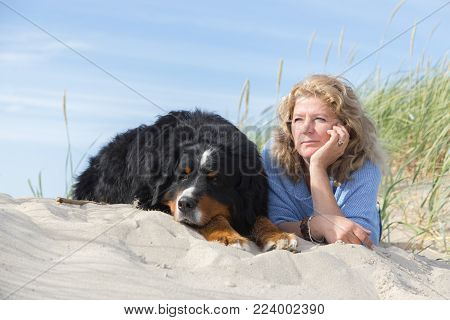 Mature Woman With Her Dog On Sand And Grass